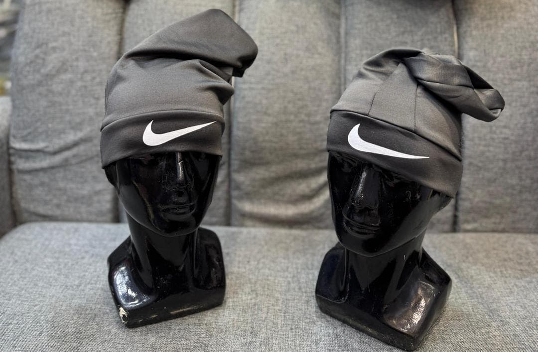 Gray Nike slouch caps with white swoosh logos on black mannequin heads.