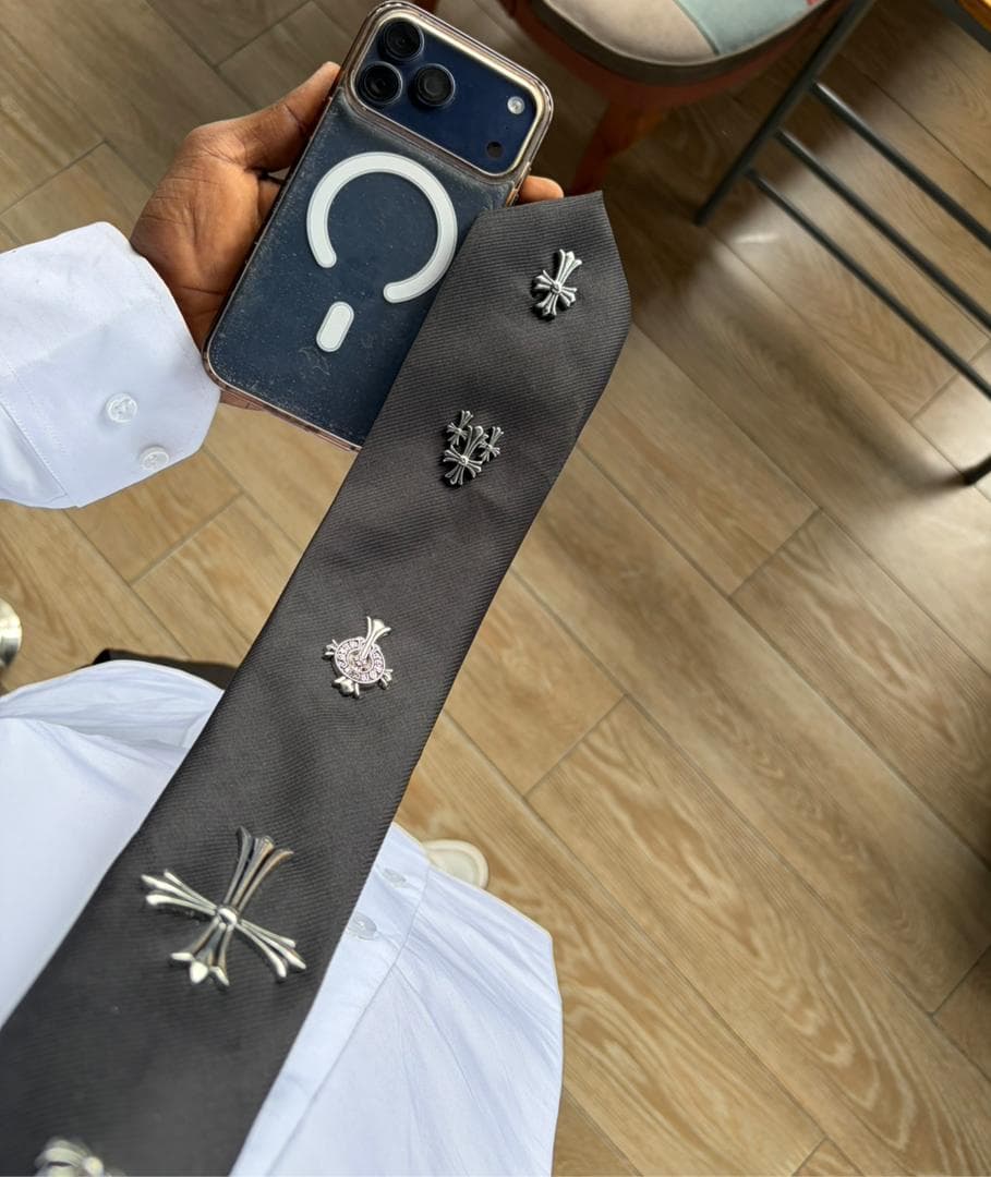 Black chrome customized tie with multiple silver cross designs including one with pink stones.
