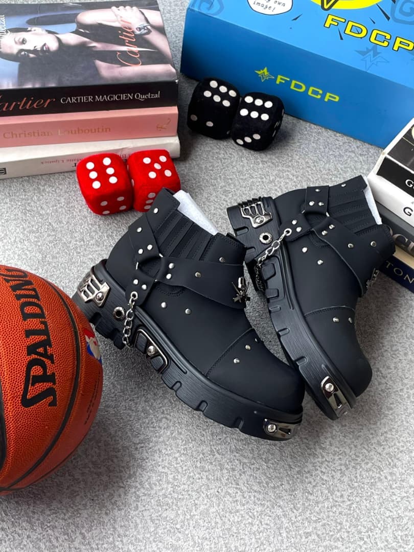 Black studded platform boots with chains surrounded by fashion books, dice and basketball.