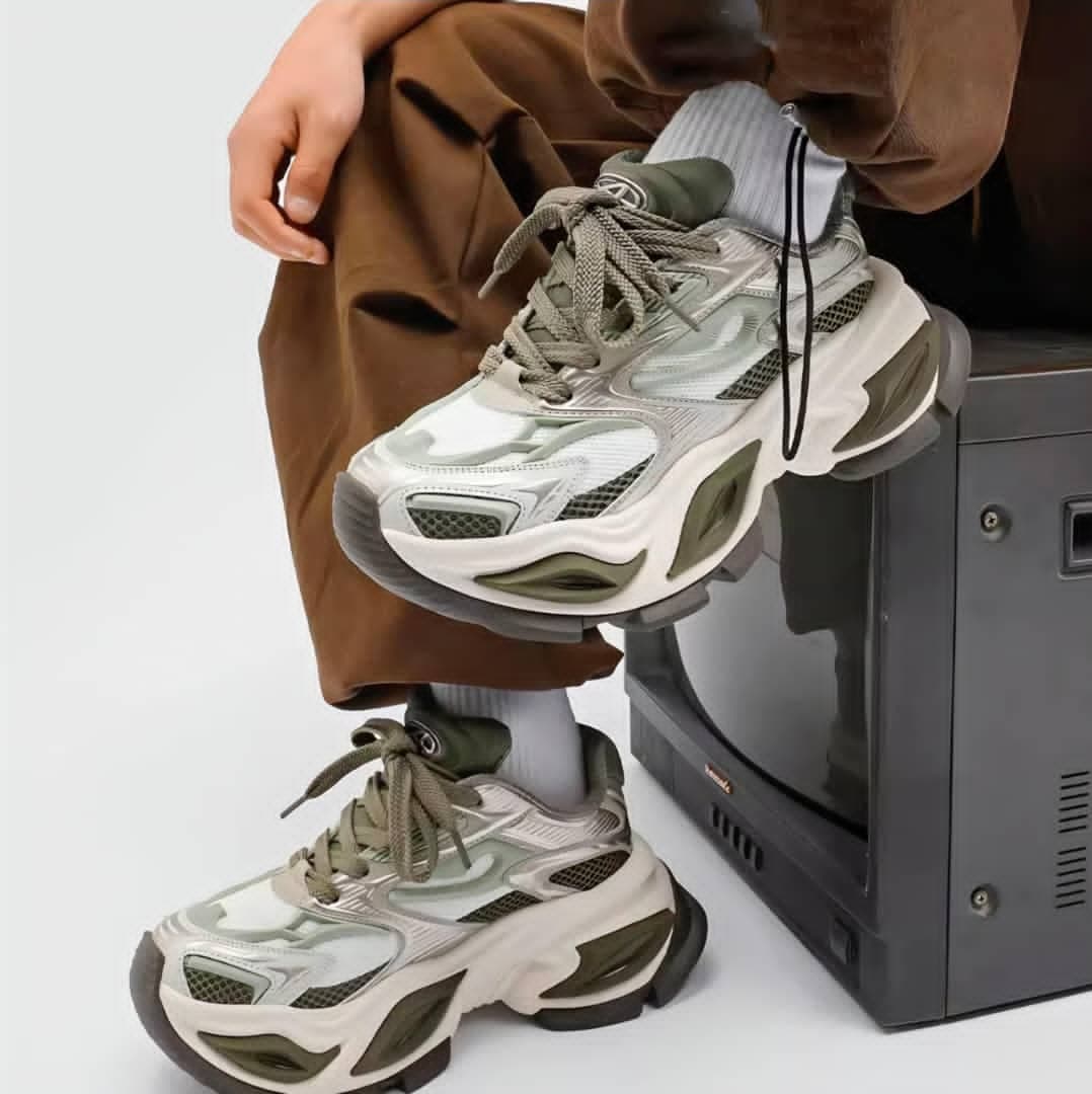 Person wearing green and beige Balenciaga Runner chunky sneakers in studio setting.