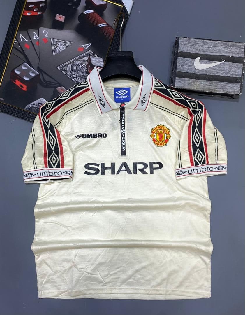 Cream Umbro Manchester United retro jersey with Sharp sponsor on display.