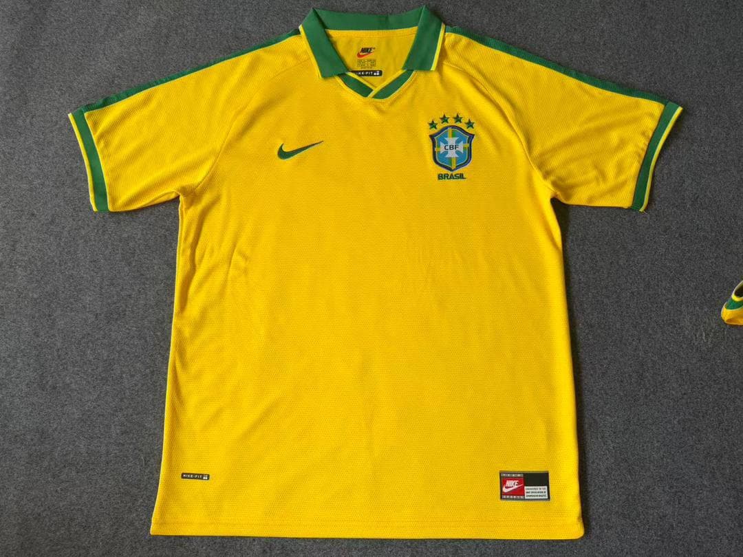Yellow Brazil national team jersey laid flat on gray surface with Nike branding.