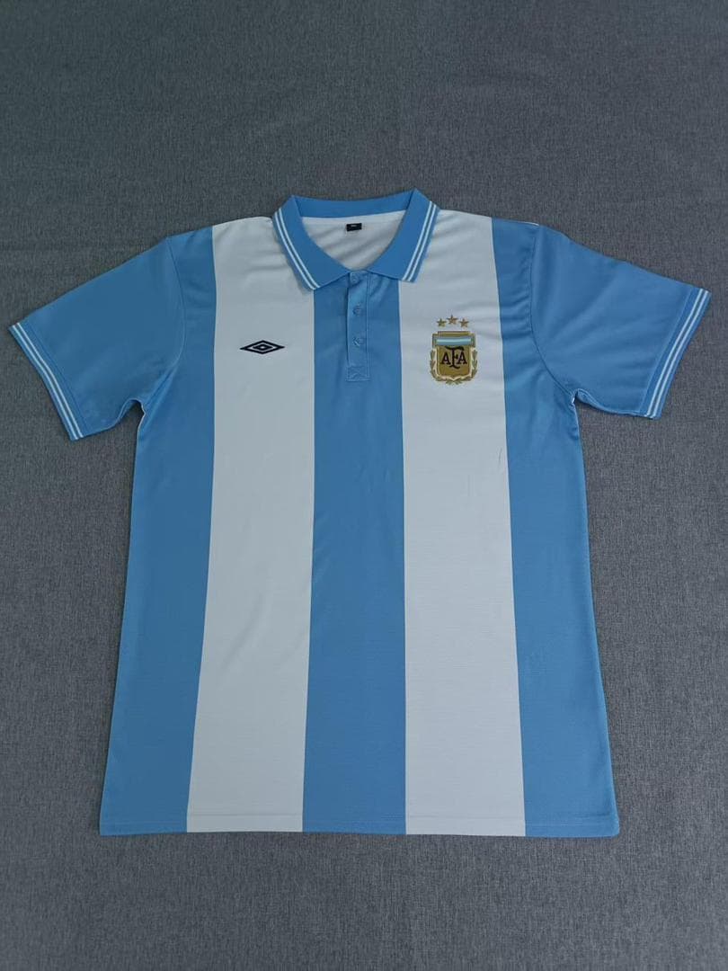 Blue and white striped Argentina polo jersey laid flat on gray surface.