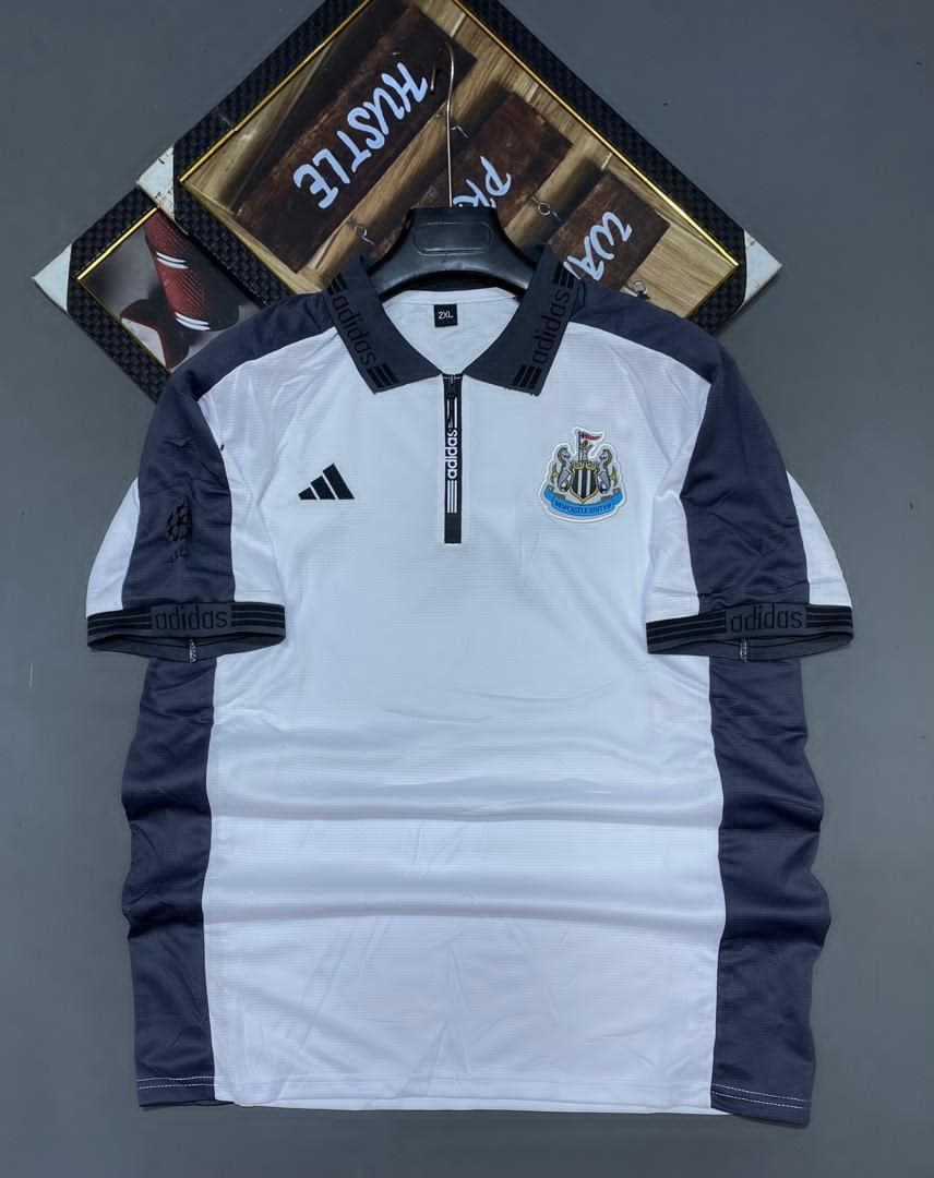 White and navy Adidas Newcastle United soccer jersey on hanger showing front with crest.