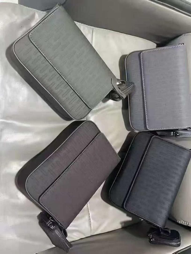 Multiple embossed monogram crossbody bags in light gray, gray, brown, black and dark gray tones.