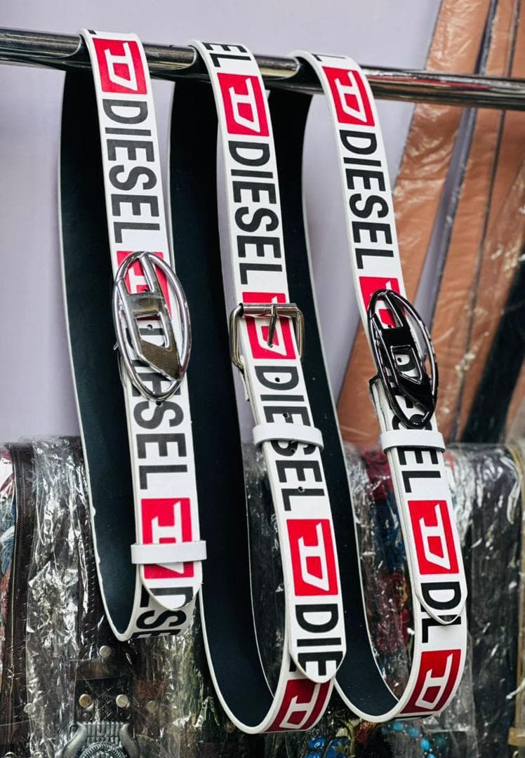Three Diesel belts hanging on a metal rack with various buckles.