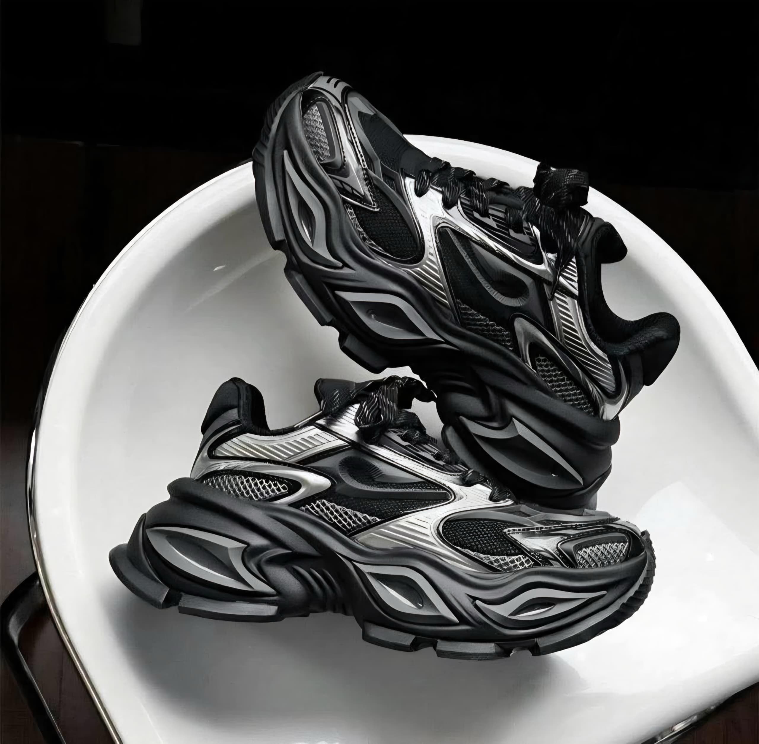 Black and silver chunky sneakers in dramatic lighting on white surface.