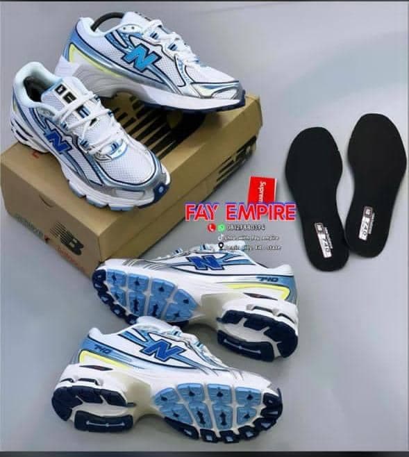 White and blue New Balance sneakers with box and black insoles on display.