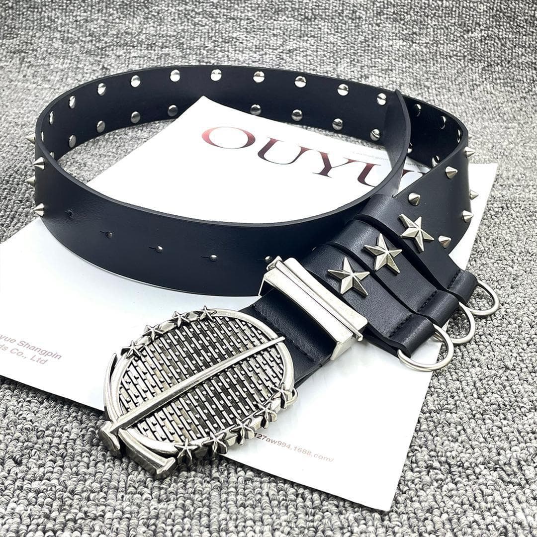 Black studded leather belt with star details and large decorative buckle displayed on a textured surface.