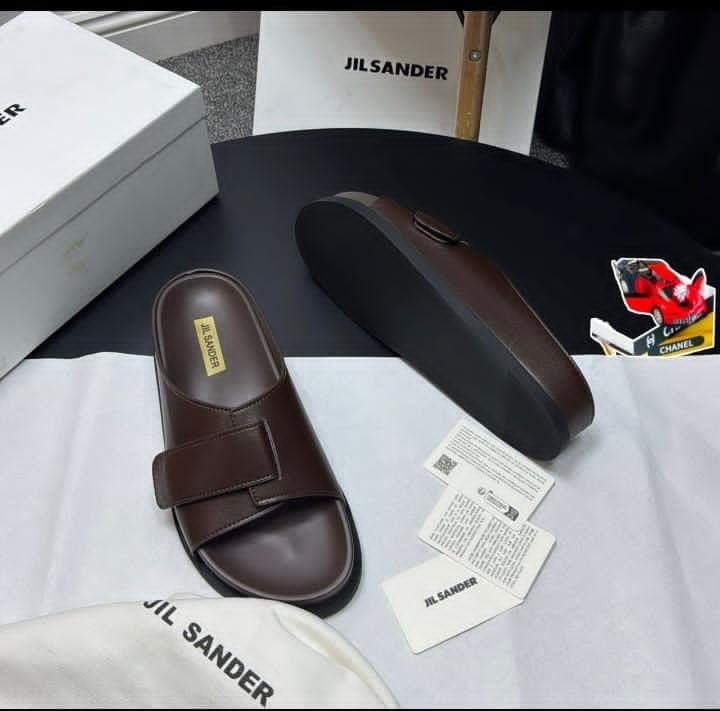 Brown Jil Sander slides with buckle shown with box, dust bag and cards.