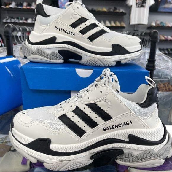 White and black Balenciaga sneakers shown from side and front angles on a blue box.