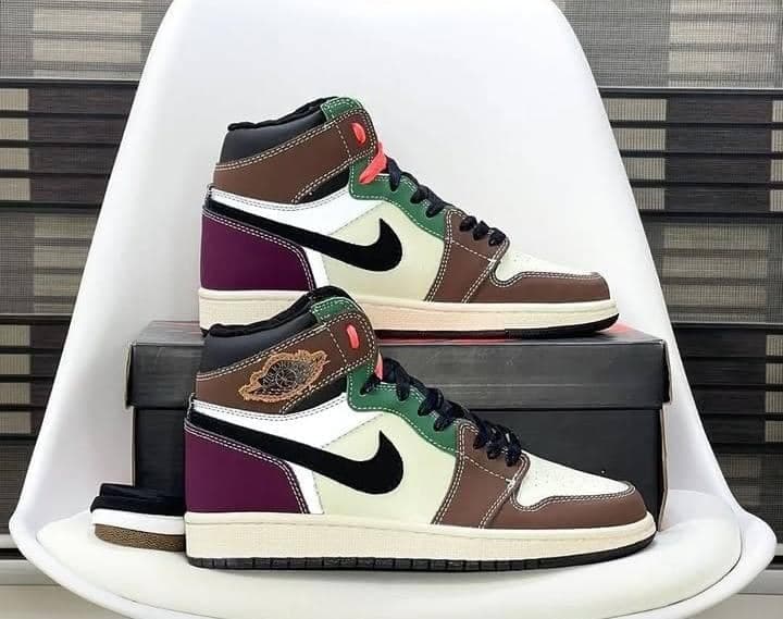 Multi-colored Jordan 1 High sneakers in brown purple green displayed on a white chair.