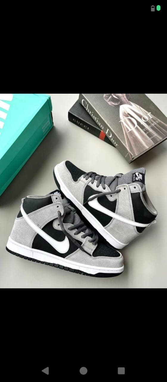 Gray and black Nike Dunk High sneakers on a flat lay with books.