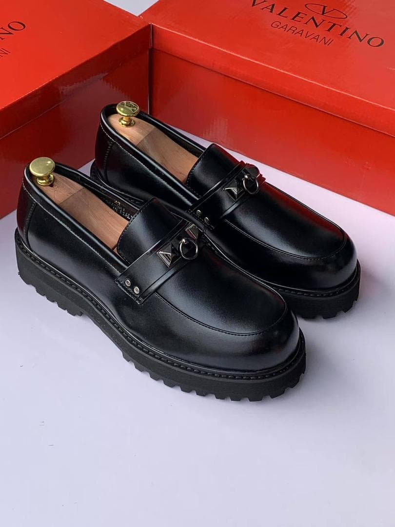 Pair of black Valentino platform loafers with red box in background.