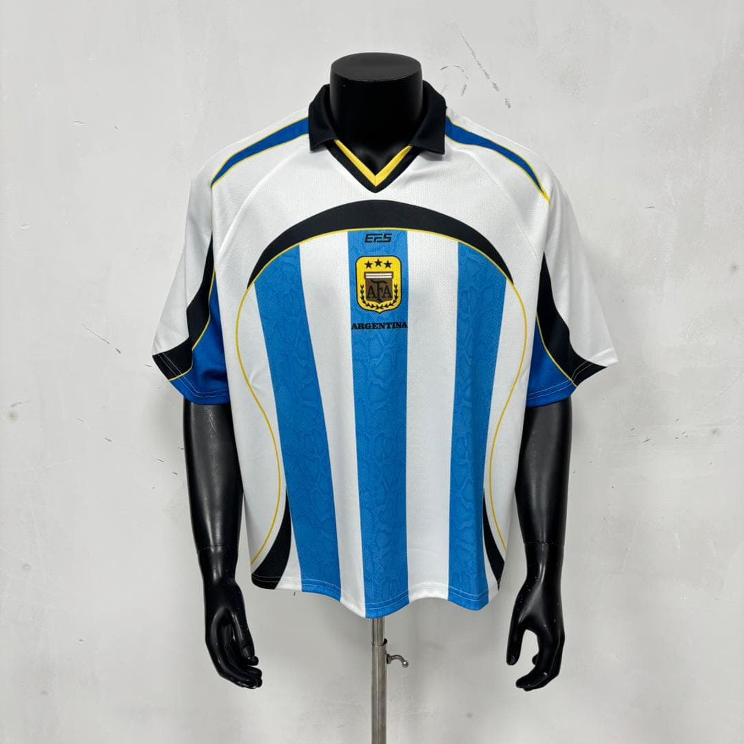 Front view of white and blue striped Argentina football jersey on mannequin showing AFA crest and ARGENTINA text.