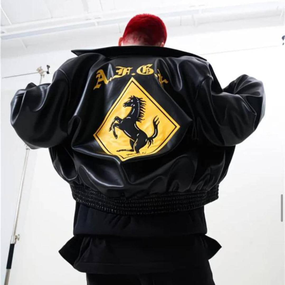 Person with red hair from behind wearing black bomber jacket with A.F.G.A text and yellow horse graphic on back.