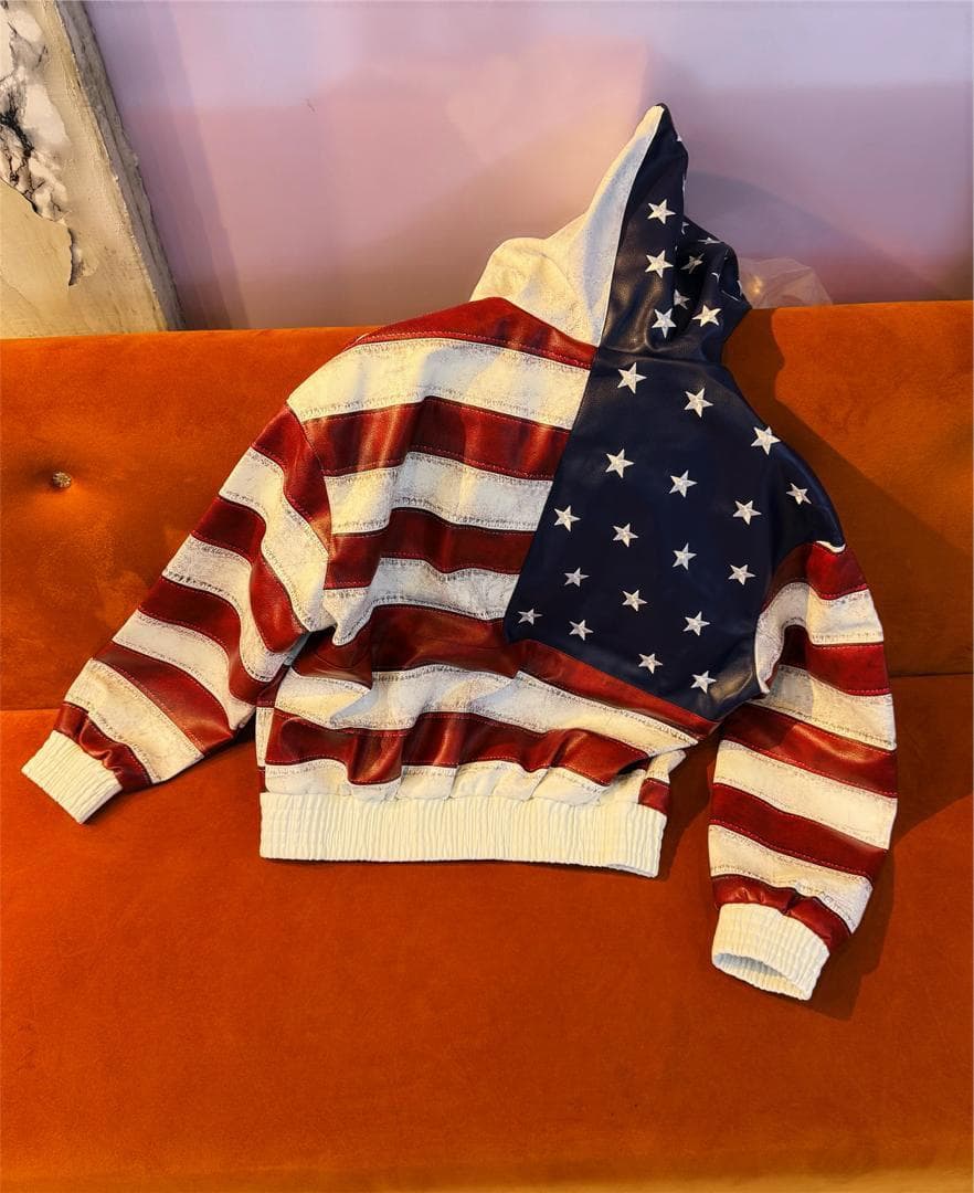 Back view of American flag hooded jacket laid flat on orange couch highlighting the design.