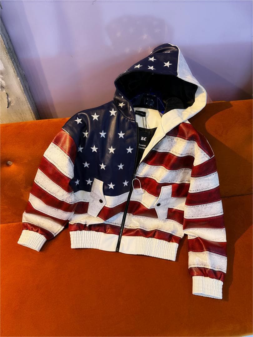 Angled front view of American flag hooded jacket laid on orange couch with hood up.