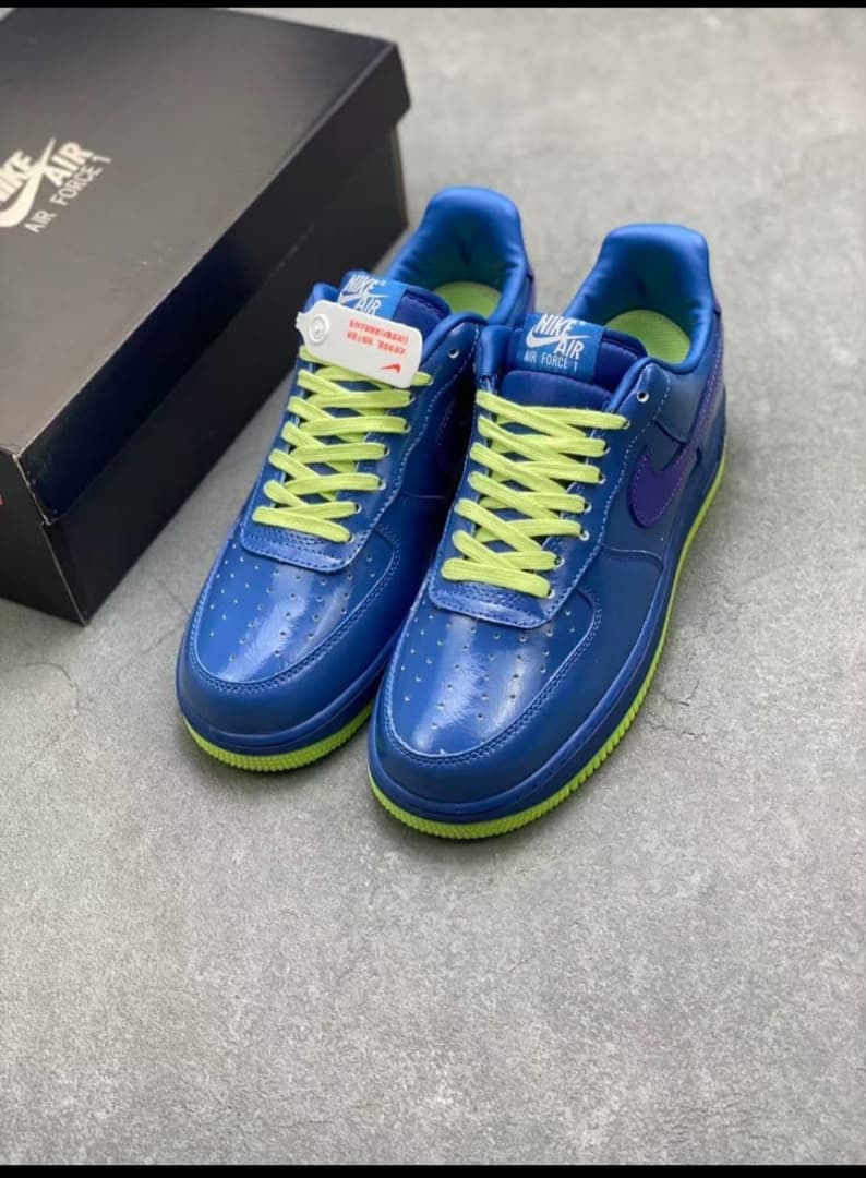 Pair of blue Nike Air Force 1 sneakers with neon yellow laces and green sole.