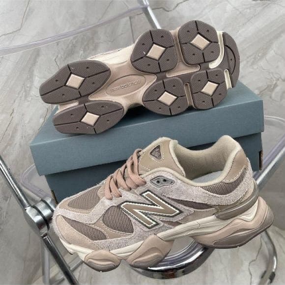 Beige New Balance 9060 sneakers shown from multiple angles with blue box on transparent stand.