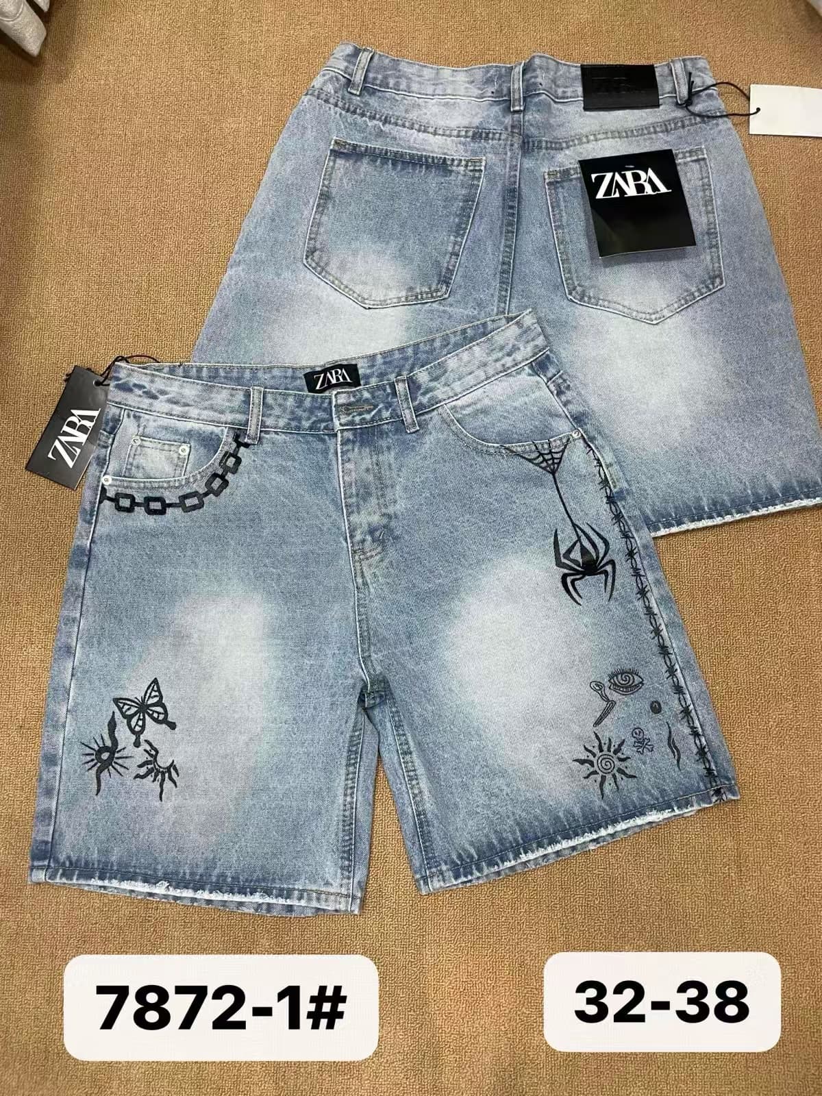 Light blue denim shorts with black embroidery of spiders, butterflies and chains.