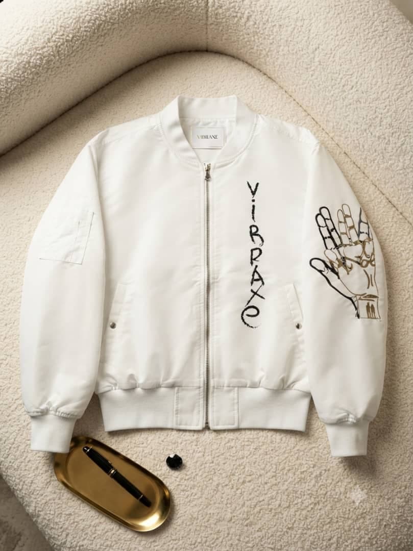 White VIBRAXE bomber jacket with black embroidery and detailed hand graphic on sleeve, displayed on textured surface.