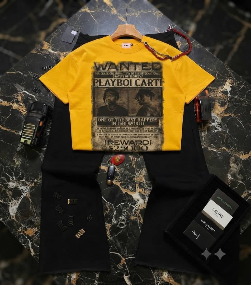 Yellow Playboi Carti wanted graphic t-shirt paired with black pants with chain detail on marble surface with accessories.