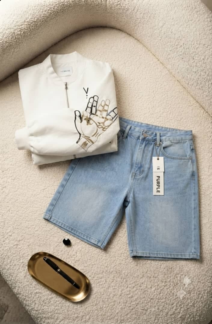 White VIBBANE bomber jacket folded to show gold and black skeleton hand graphic beside light blue denim shorts.