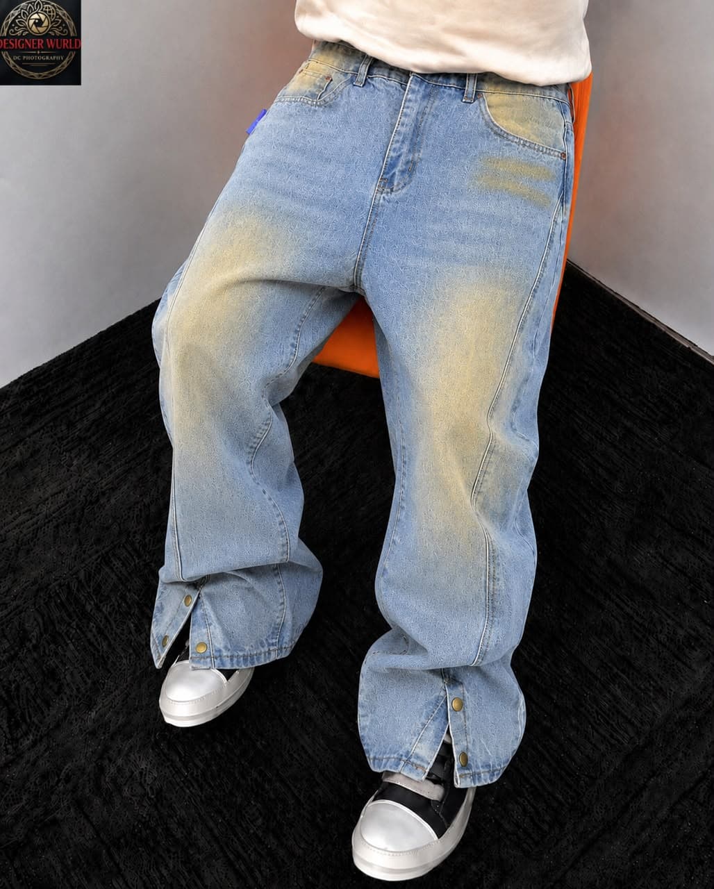 Model in light blue acid wash baggy jeans with yellow bleach and buttoned hem slits.