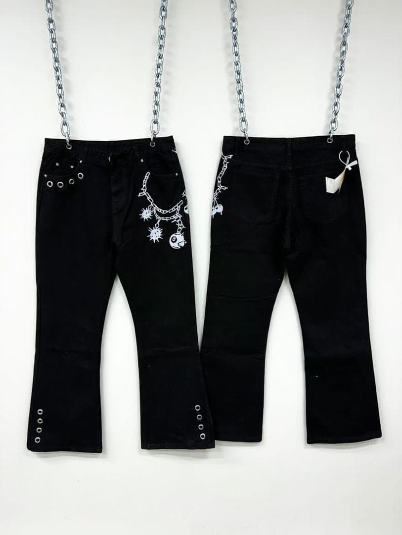 Back view of black baggy jeans with white chain skull and spike prints hanging from metal chains.