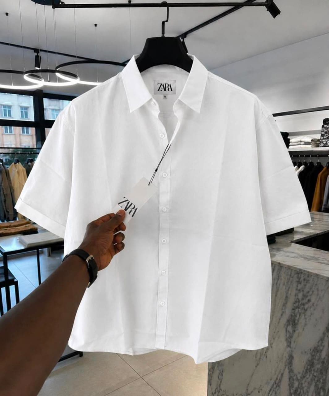 White Zara short sleeve button-up shirt on hanger with tag.