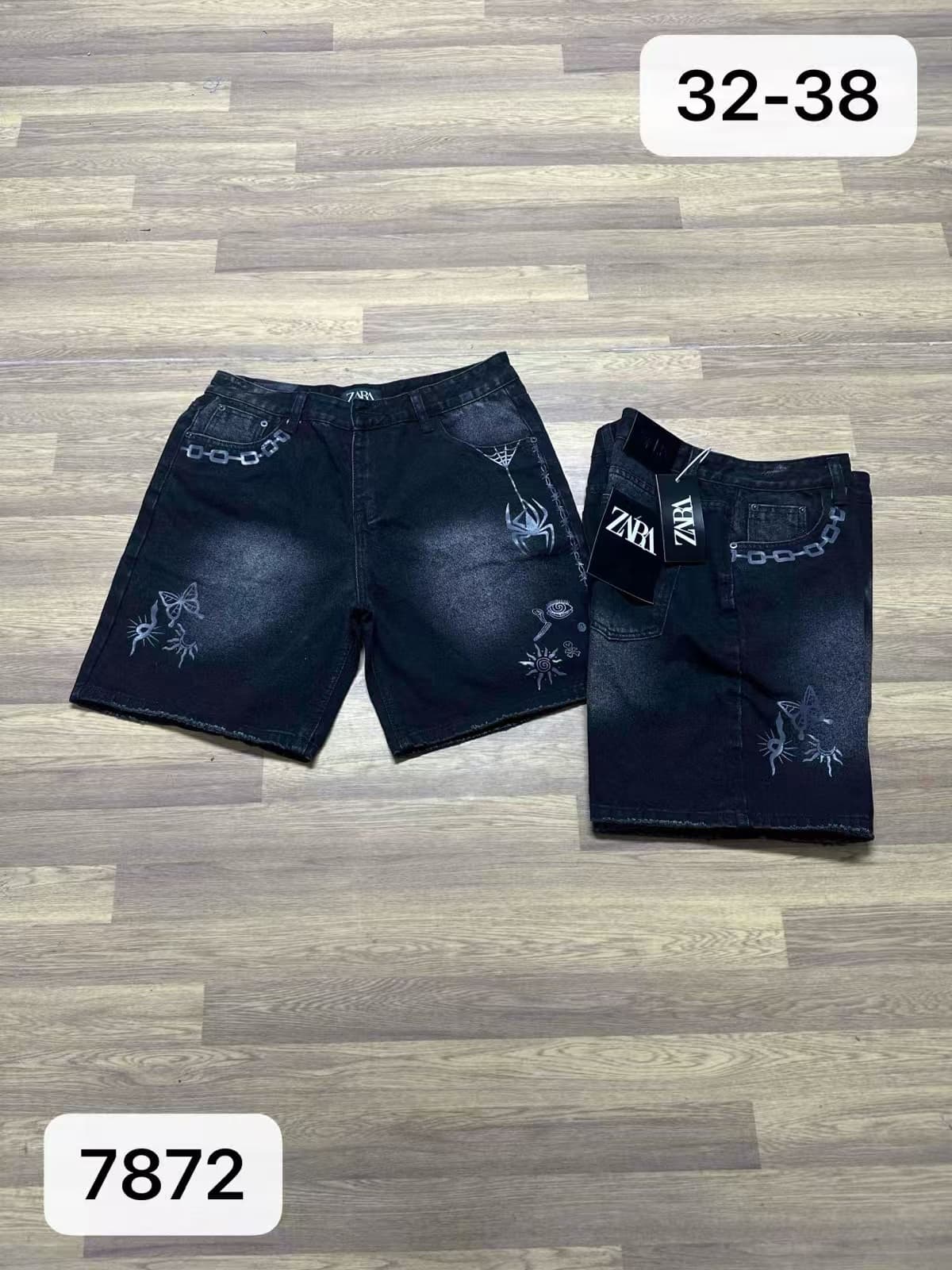Black denim shorts with white embroidery of butterflies, spider, chains and symbols.