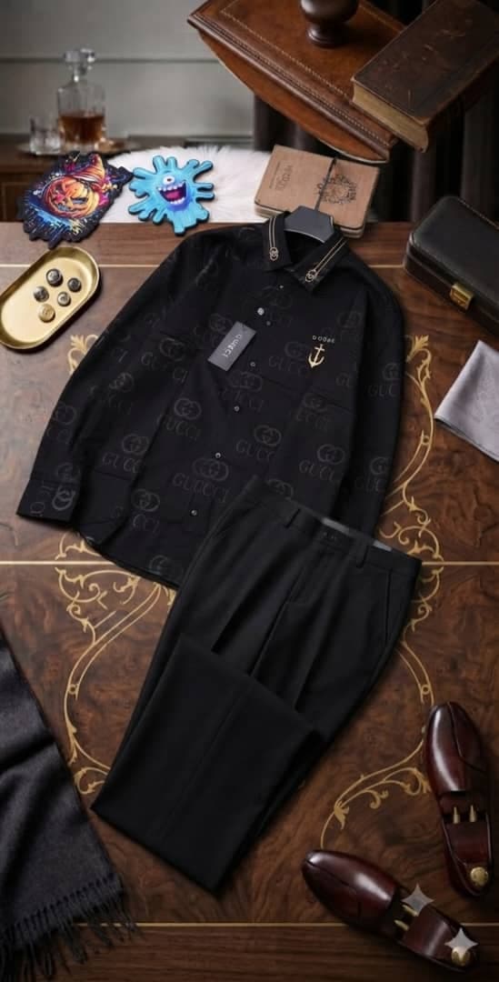 Black Gucci monogram long-sleeve shirt and black trousers styled on ornate table with accessories.