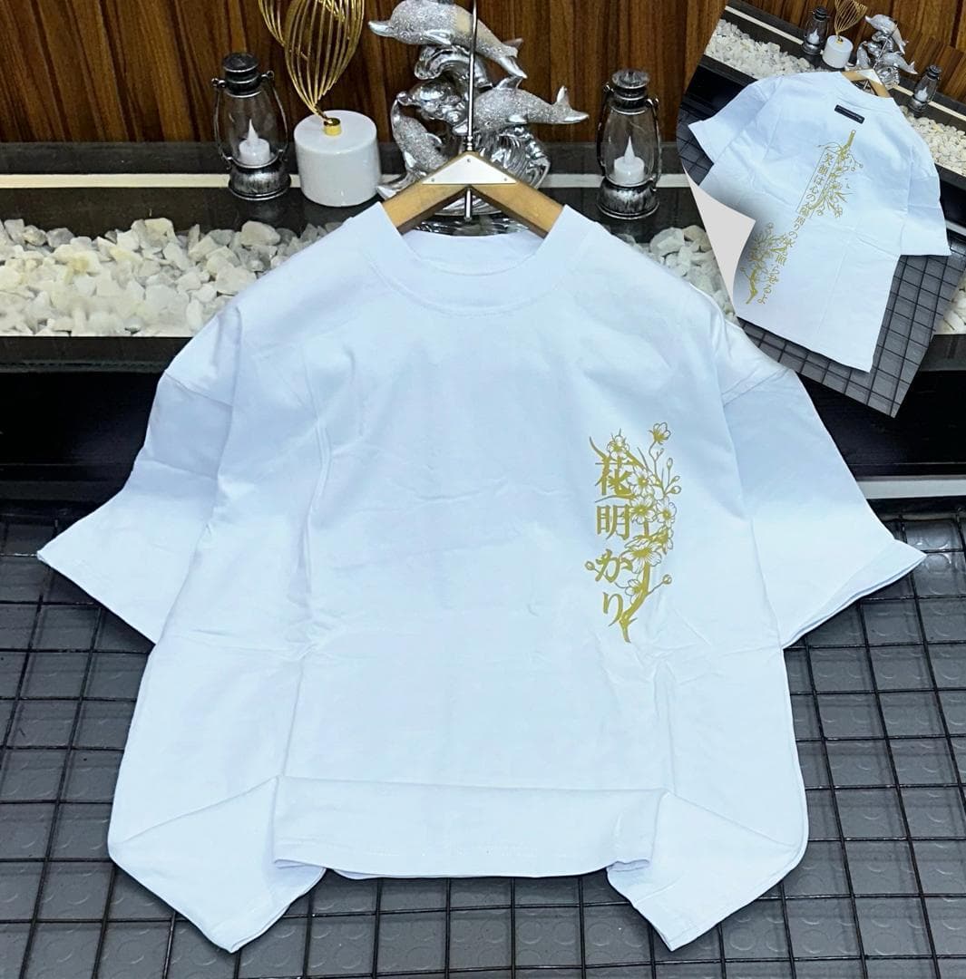 White oversized t-shirt with gold floral Japanese characters design on the side with inset view.