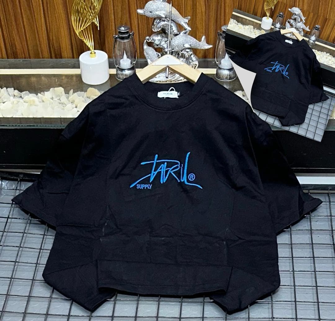 Black oversized t-shirt with blue Jaril Supply script logo on grid with inset view.