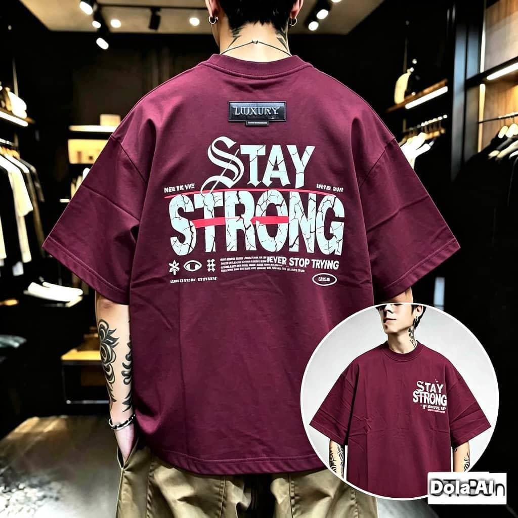 Man in burgundy Stay Strong graphic oversized t-shirt showing back with large text and symbols, plus front inset.