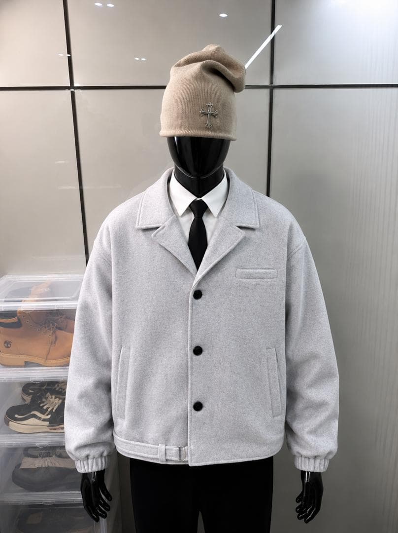 Gray wool button jacket on mannequin styled with shirt, tie, and beanie.