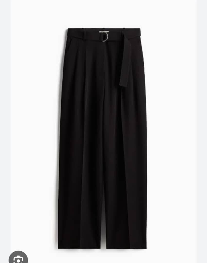 Black pleated wide-leg flare pants with D-ring belt against white background.