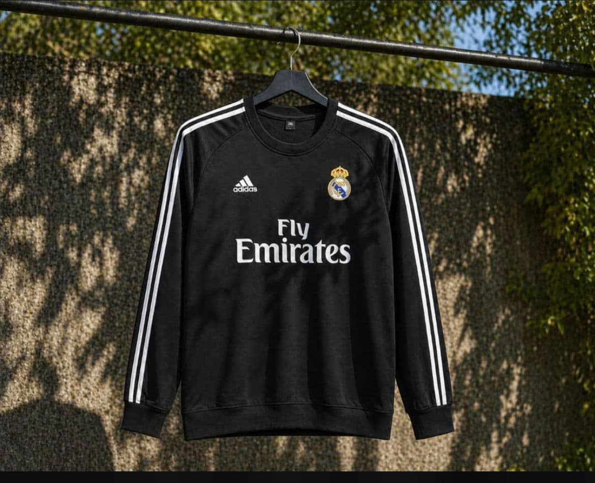 Black Real Madrid long sleeve jersey with white stripes and Fly Emirates sponsor.