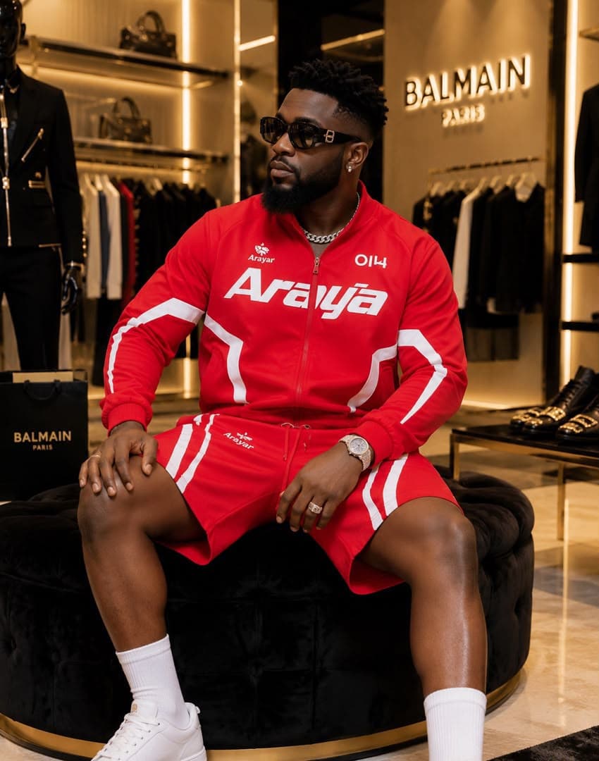 Man seated in luxury store wearing red Araya zip jacket and matching shorts with white stripes.