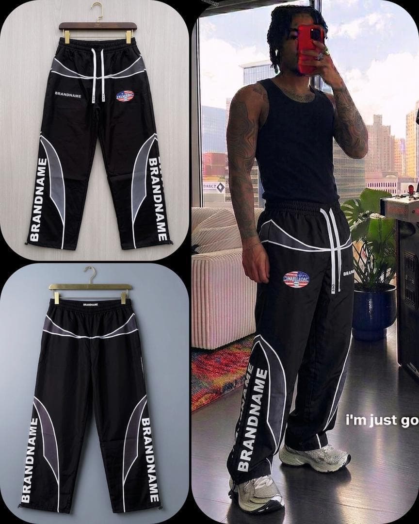 Flat lay and model wearing black track joggers with white vertical lettering and gray curved accents.