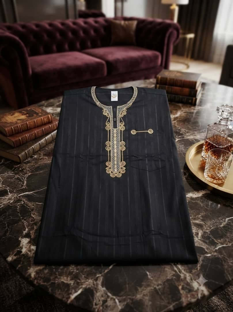 Black striped jalabia with gold embroidery displayed with books.