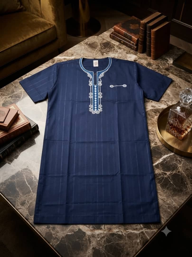 Navy blue striped jalabia with blue embroidery on marble table.