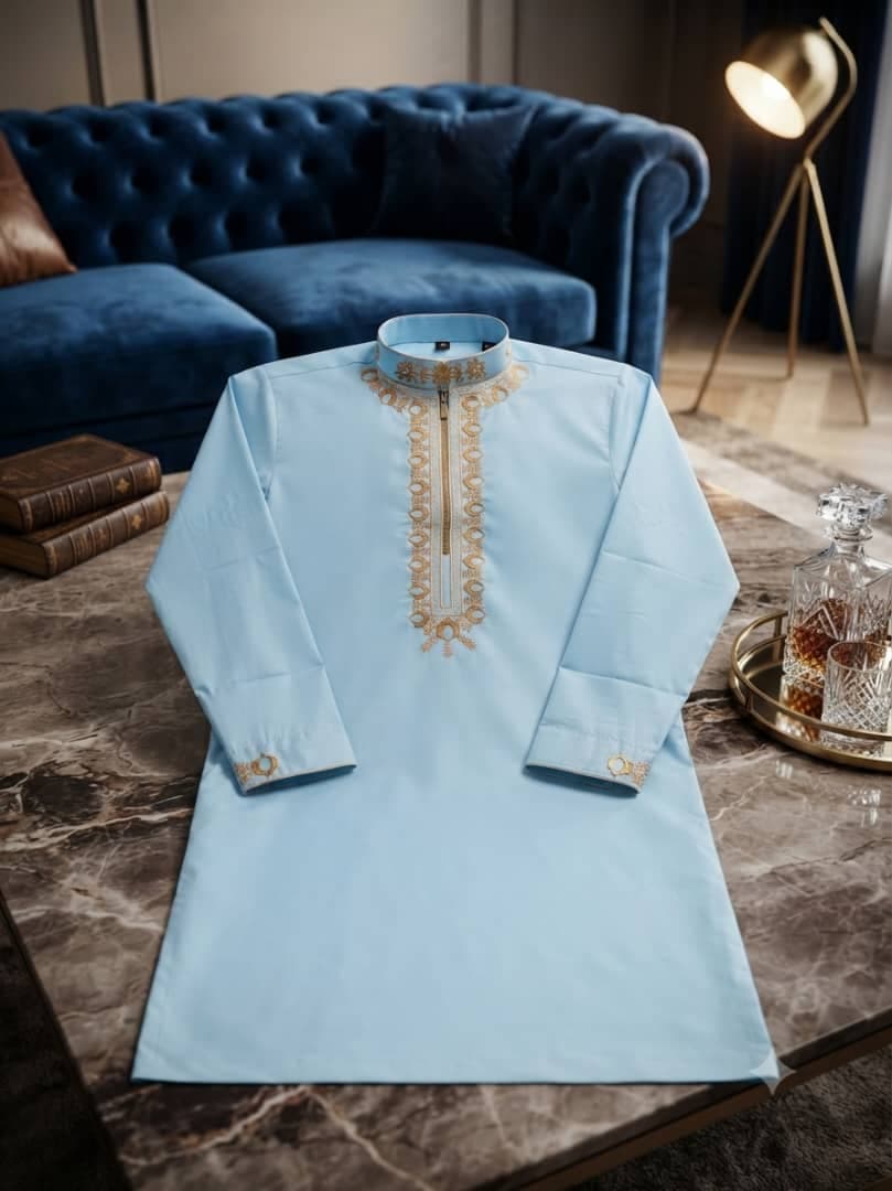 Light blue long sleeve jalabia with gold embroidery on marble table.
