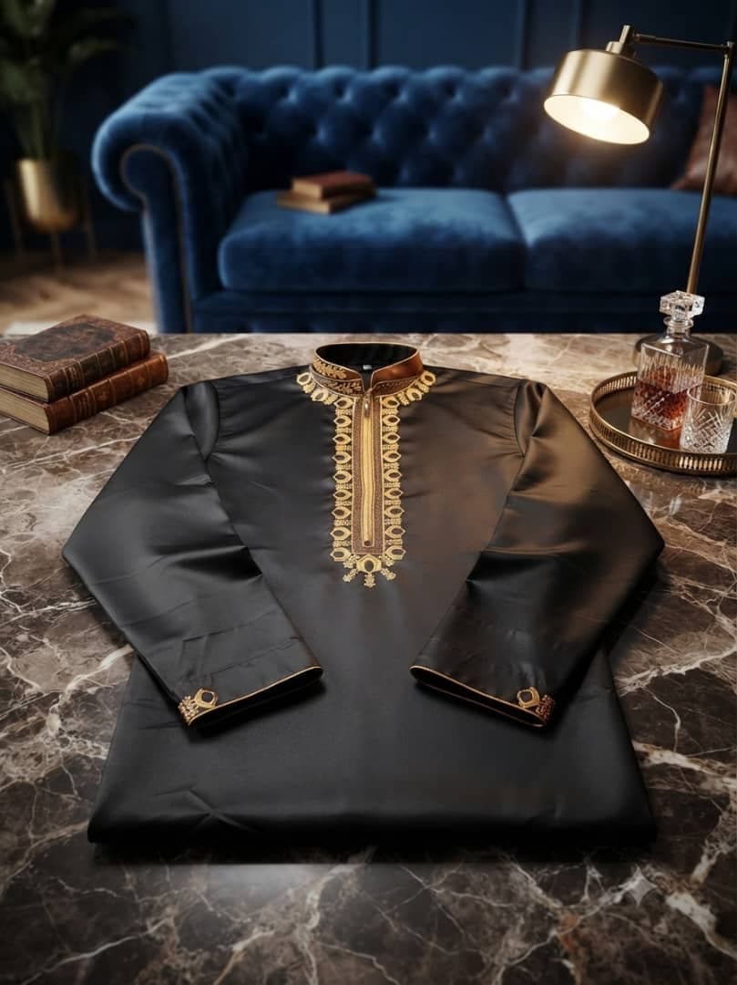 Black long sleeve jalabia with gold embroidery on marble table.