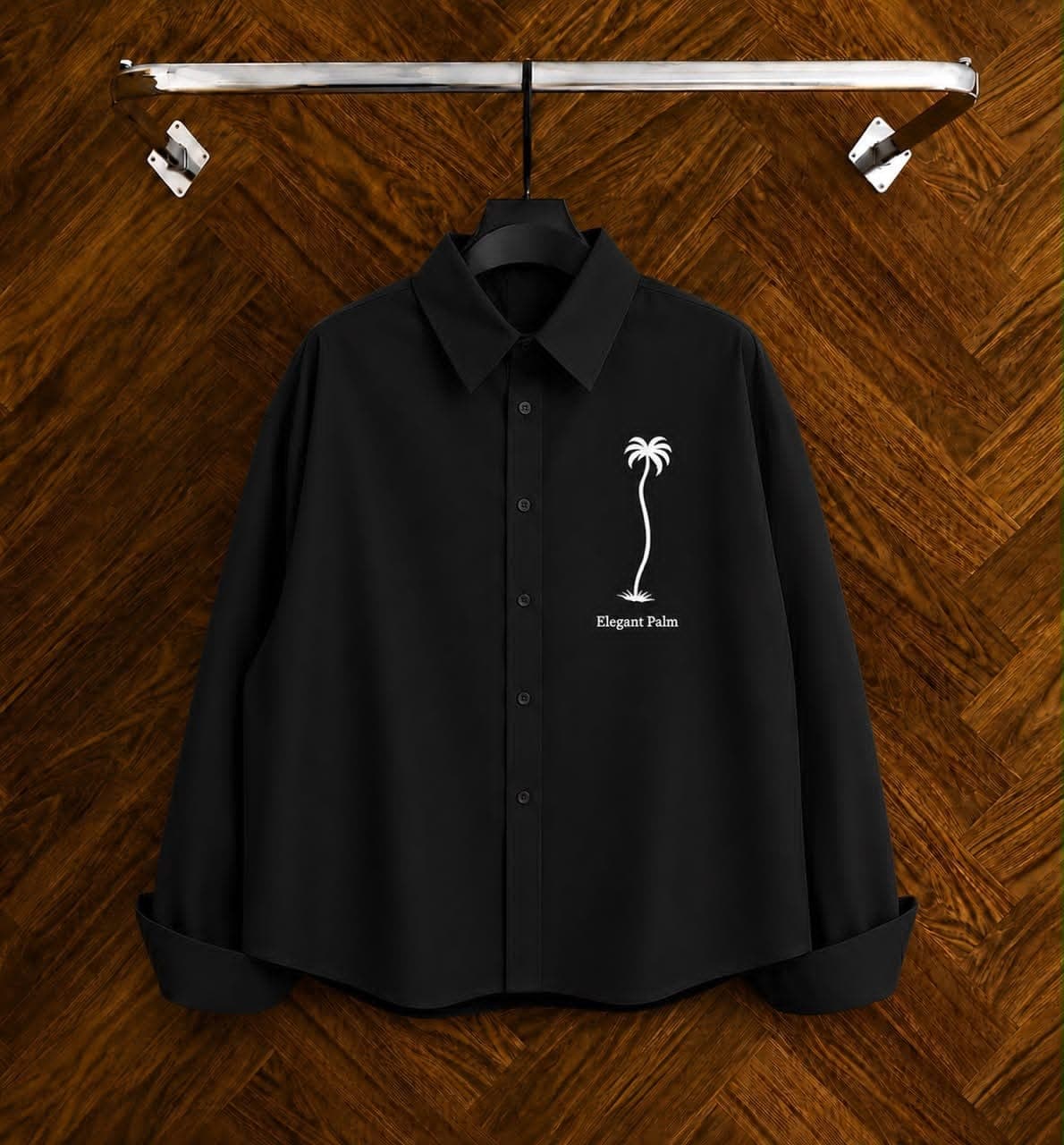 Black long sleeve shirt with palm tree embroidery on wooden hanger.