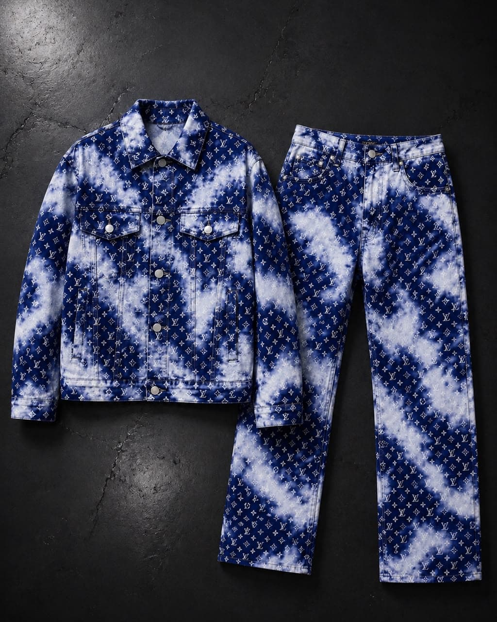 Blue and white tie-dye monogram print denim jacket and pants flat lay on dark background.