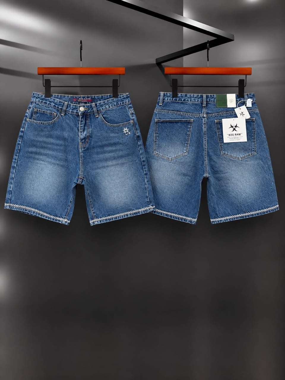 Two blue denim shorts hanging side by side showing different pocket embroidery and tags.