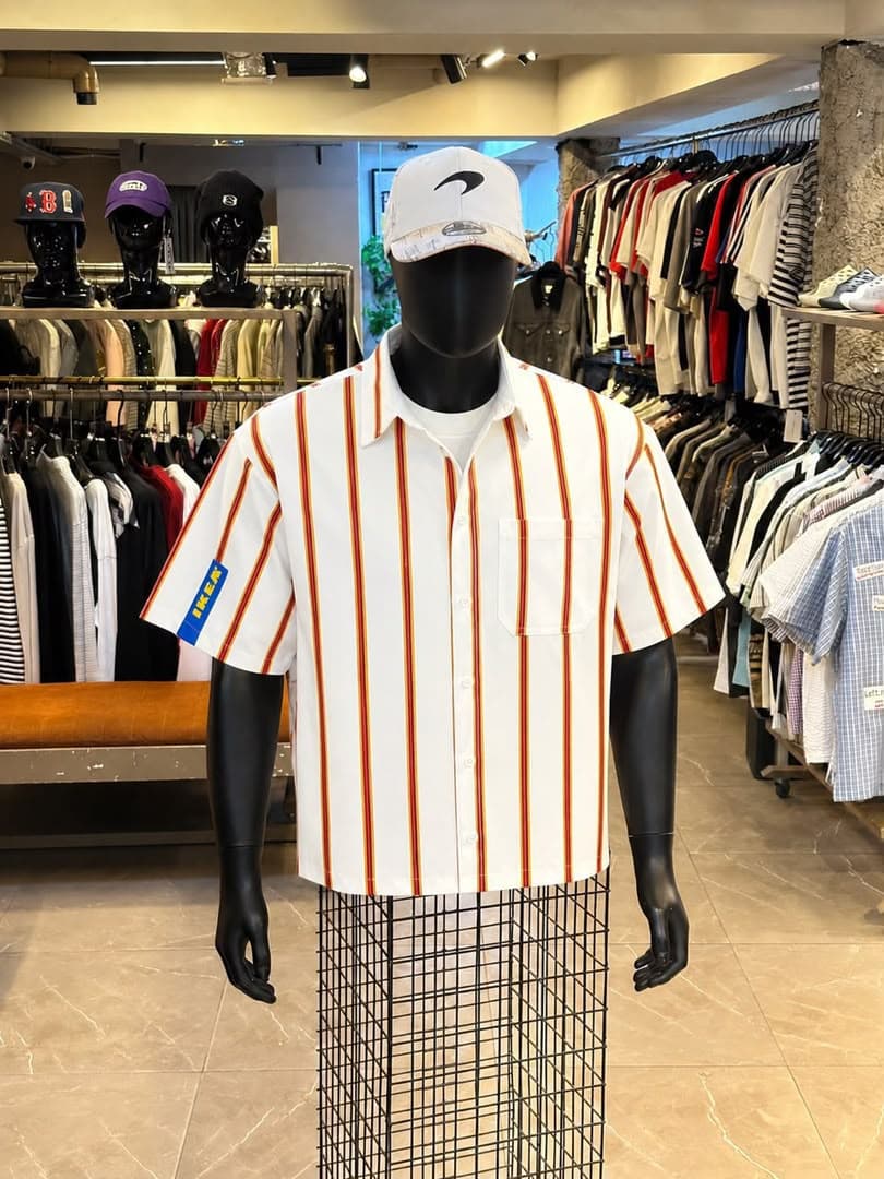 White striped short sleeve button-up shirt on mannequin with blue sleeve patch.