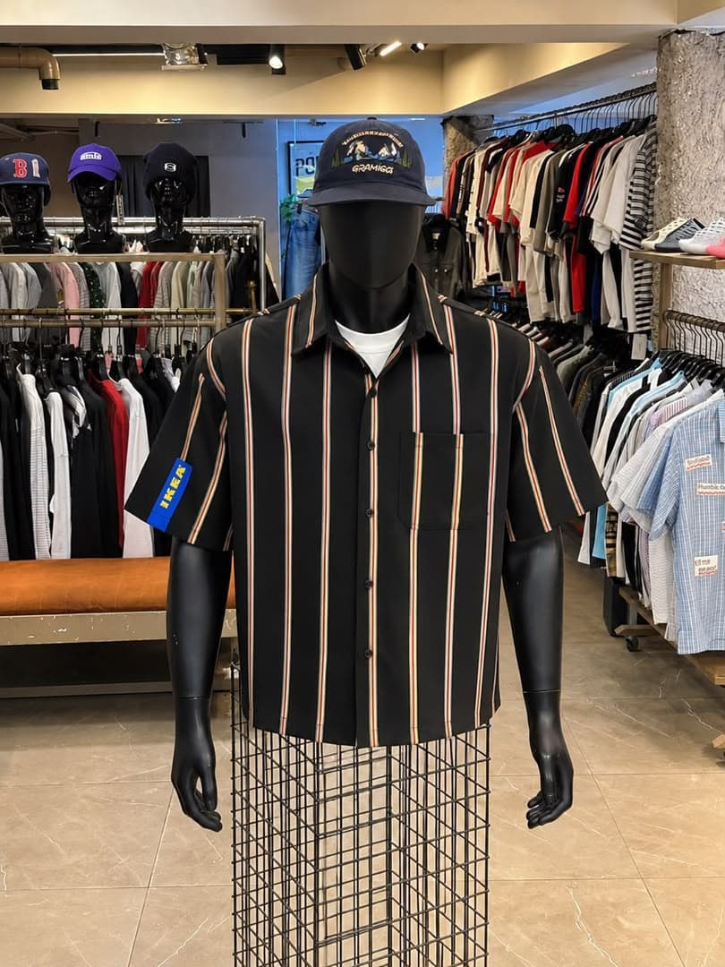 Black striped short sleeve button-up shirt on mannequin with blue sleeve patch.